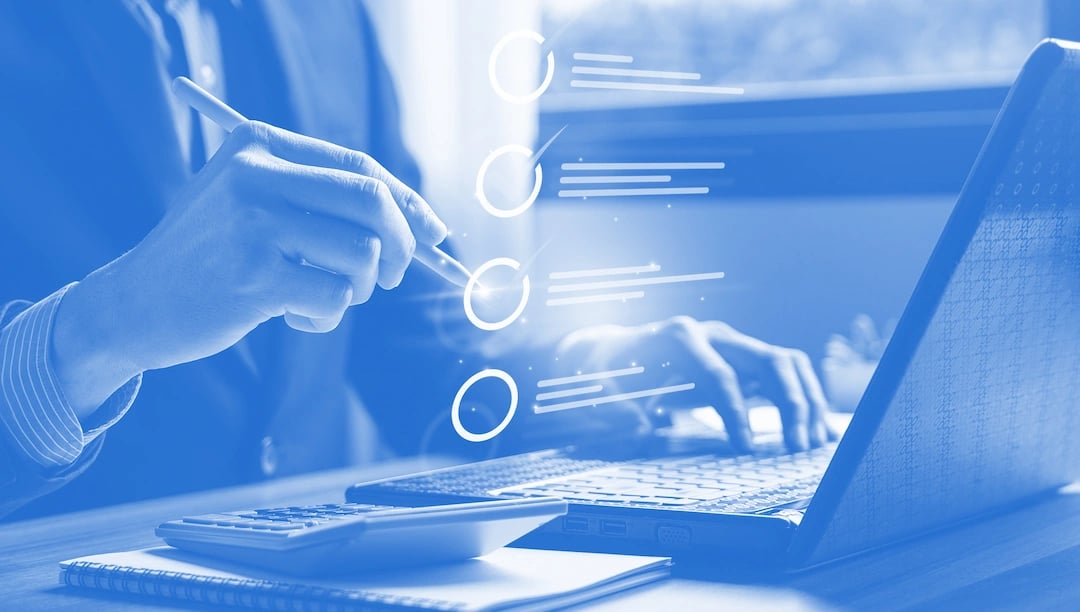 Compliance department employee typing on a laptop by his desk and checking to do list