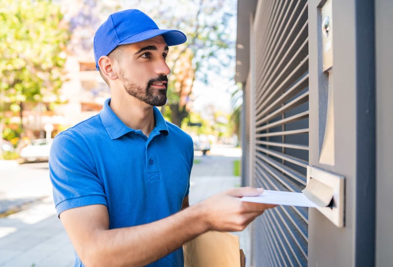 Delivery man passing letter through the door