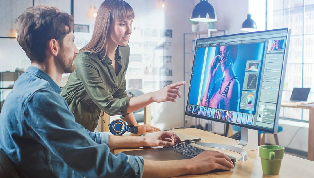 Graphic designers working together by the imac, discussing project feedback
